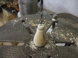	Over at the drill press the handle is drilled with a hole the size of the nail to be inserted	